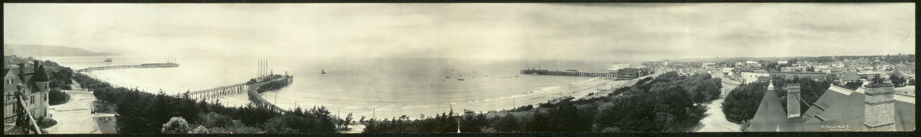 Panoramic view of coastline with piers and town — historic image