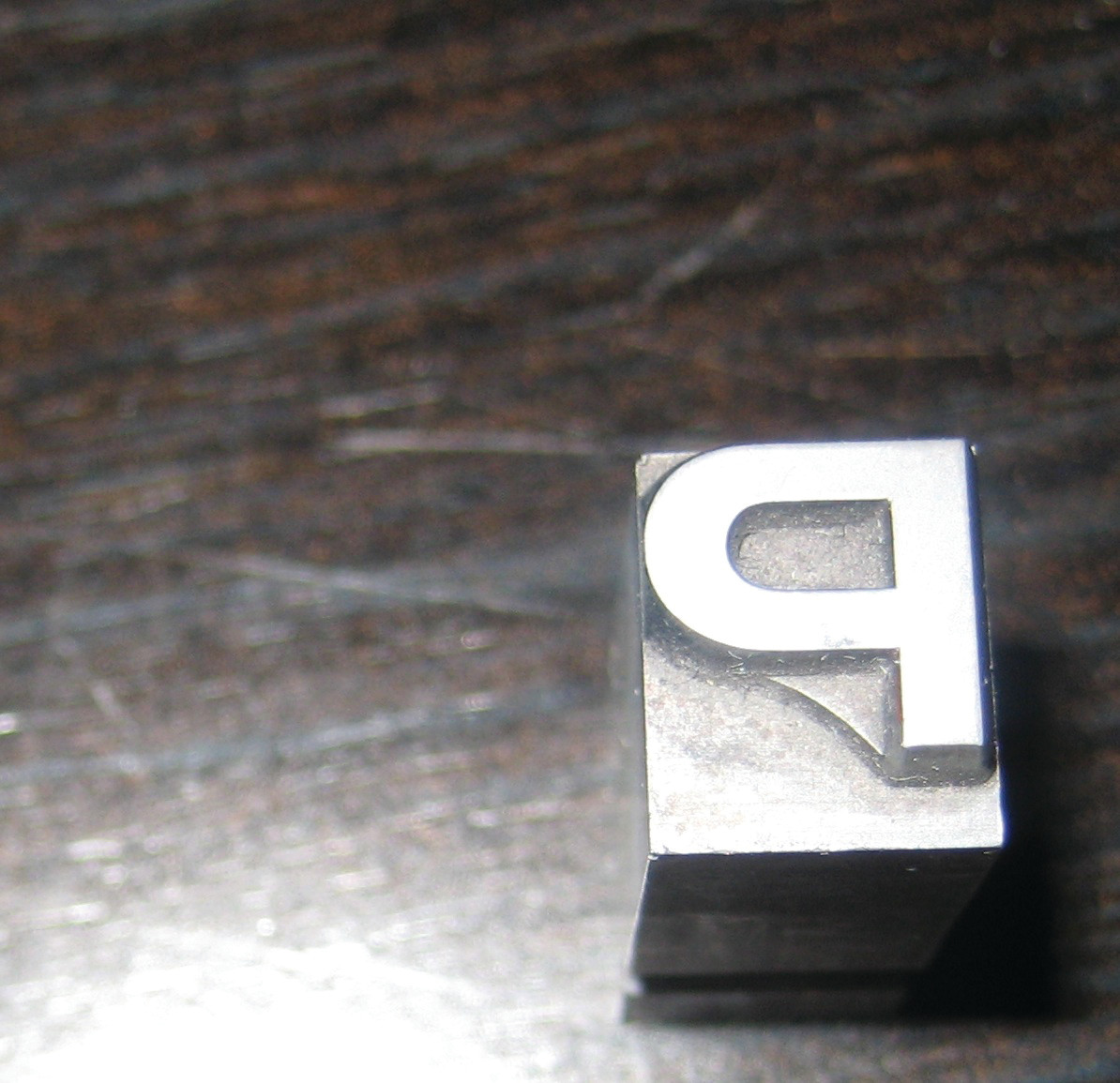 Metal letterpress type block on dark wood surface — historic image