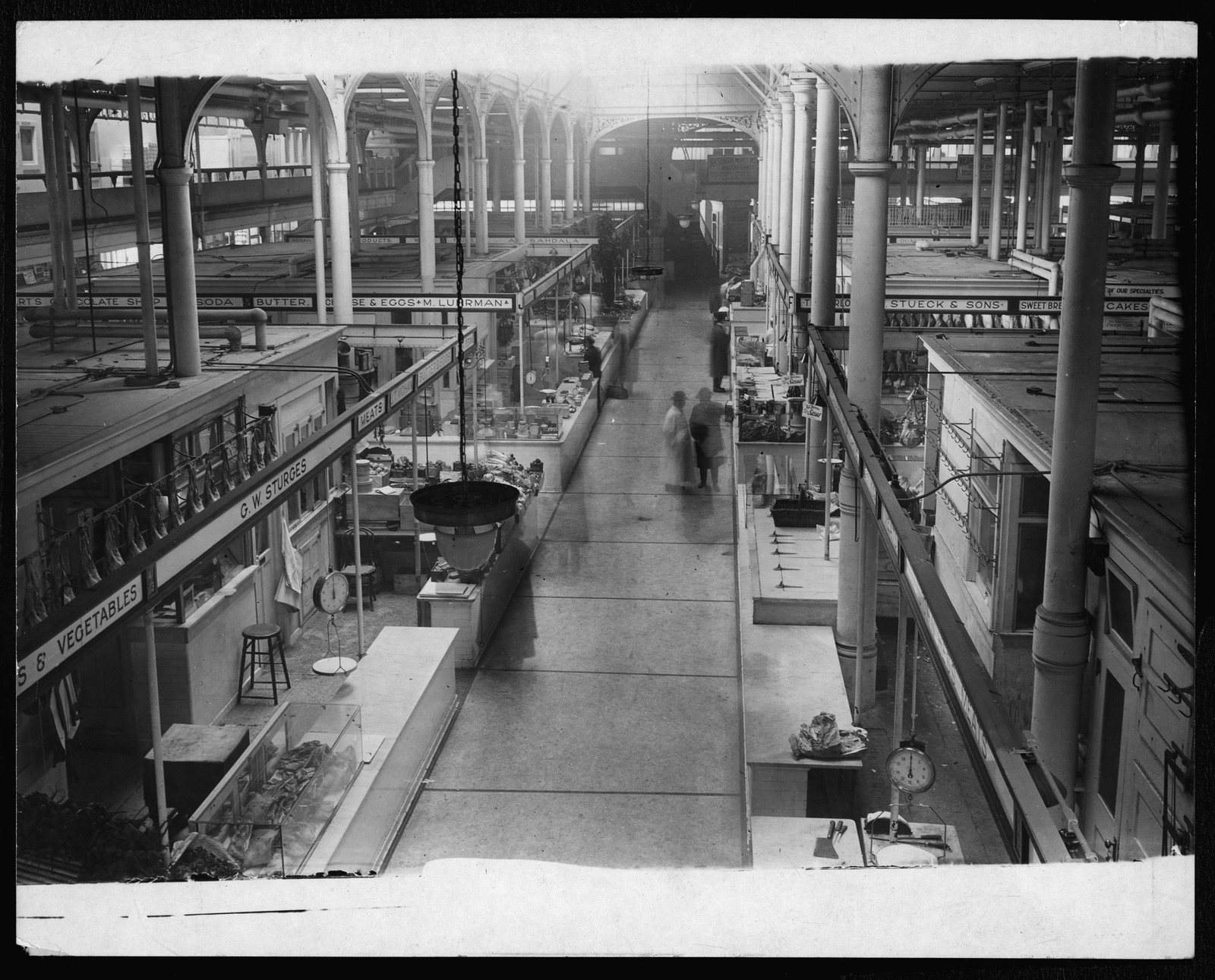 Interior of a covered market with stalls and signs — historic image
