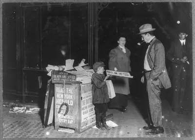 Jerald Schaitberger of 416 W. 57th St. N.Y. who helps an older boy sell papers until 10 P.M. on Columbus Circle. 7 yrs. old. 9:30 P.M., October 8, 1910. Location: New York, New York (State) / Photo by Paul B. Schumm.