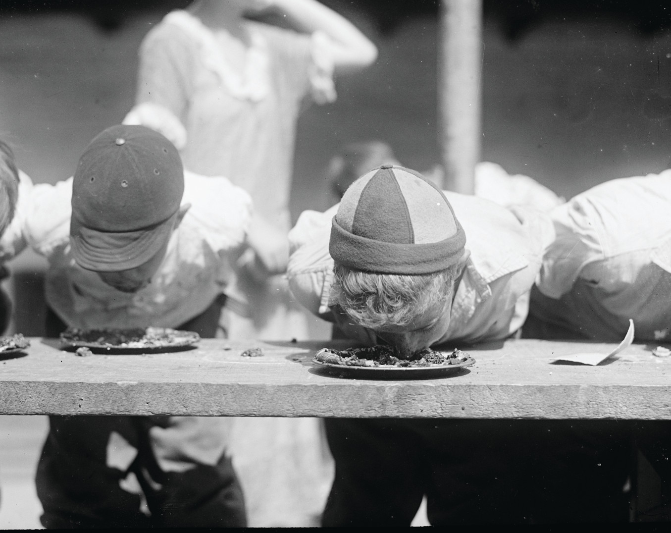 Boys with faces in pies at a pie-eating contest — historic image