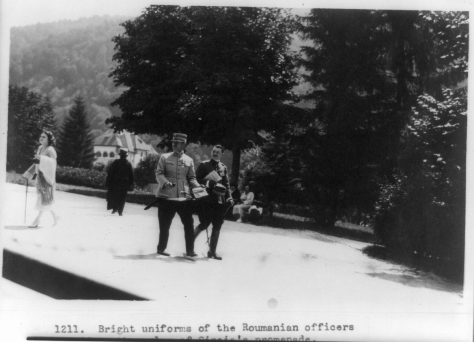 Bright uniforms of the Roumanian officers add to the color of Sinaia's promenade. Rumors have it that corsets and cosmetics often form a part of the officer's equipment in this gay country of the east, [1923] — historic photograph