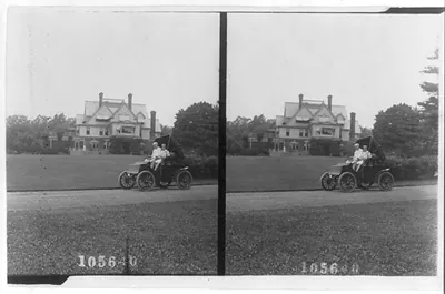 Thomas A. Edison and son(?) in automobile and large housein background