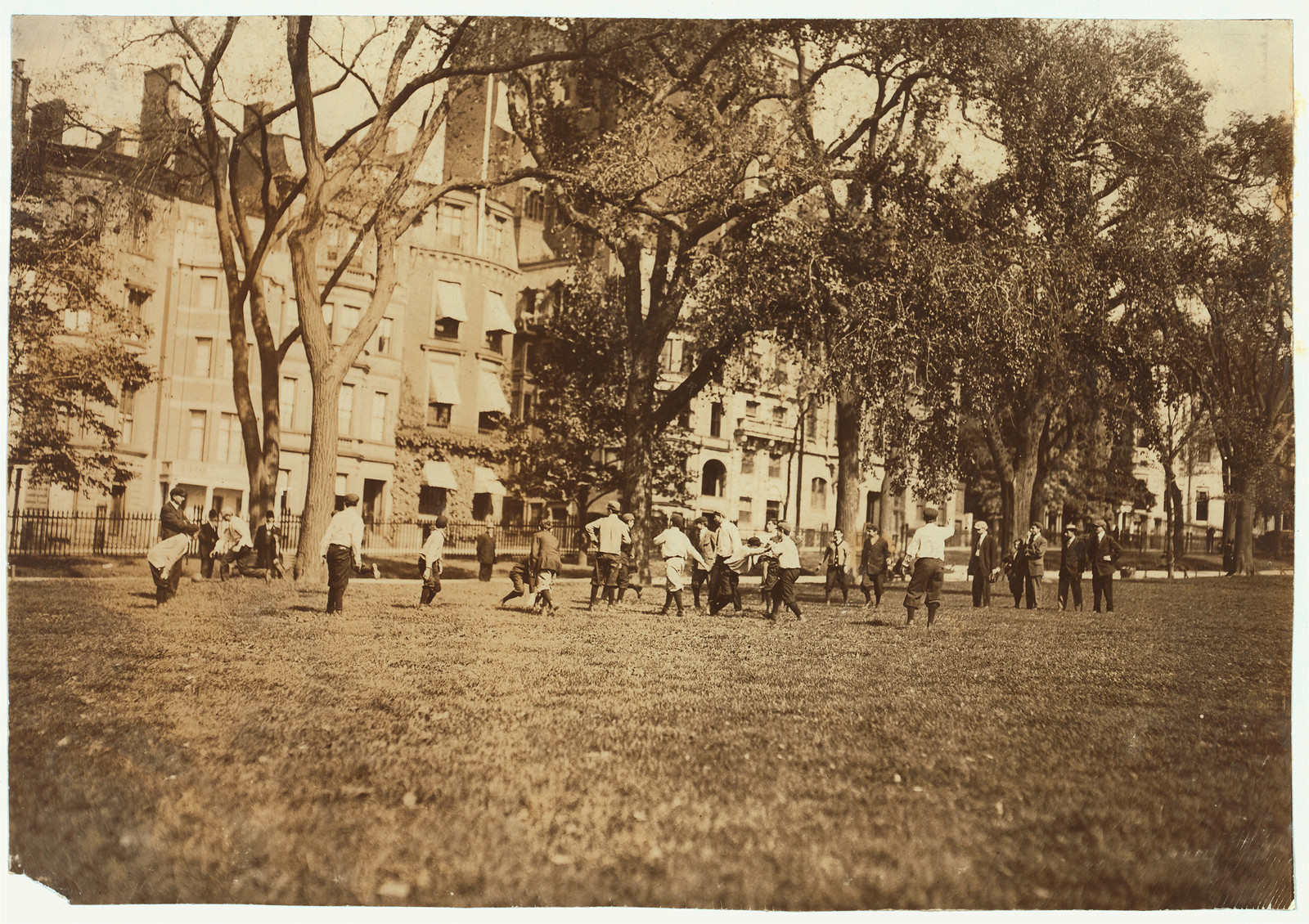 Boys playing football on a city park lawn, 1909 — historic image