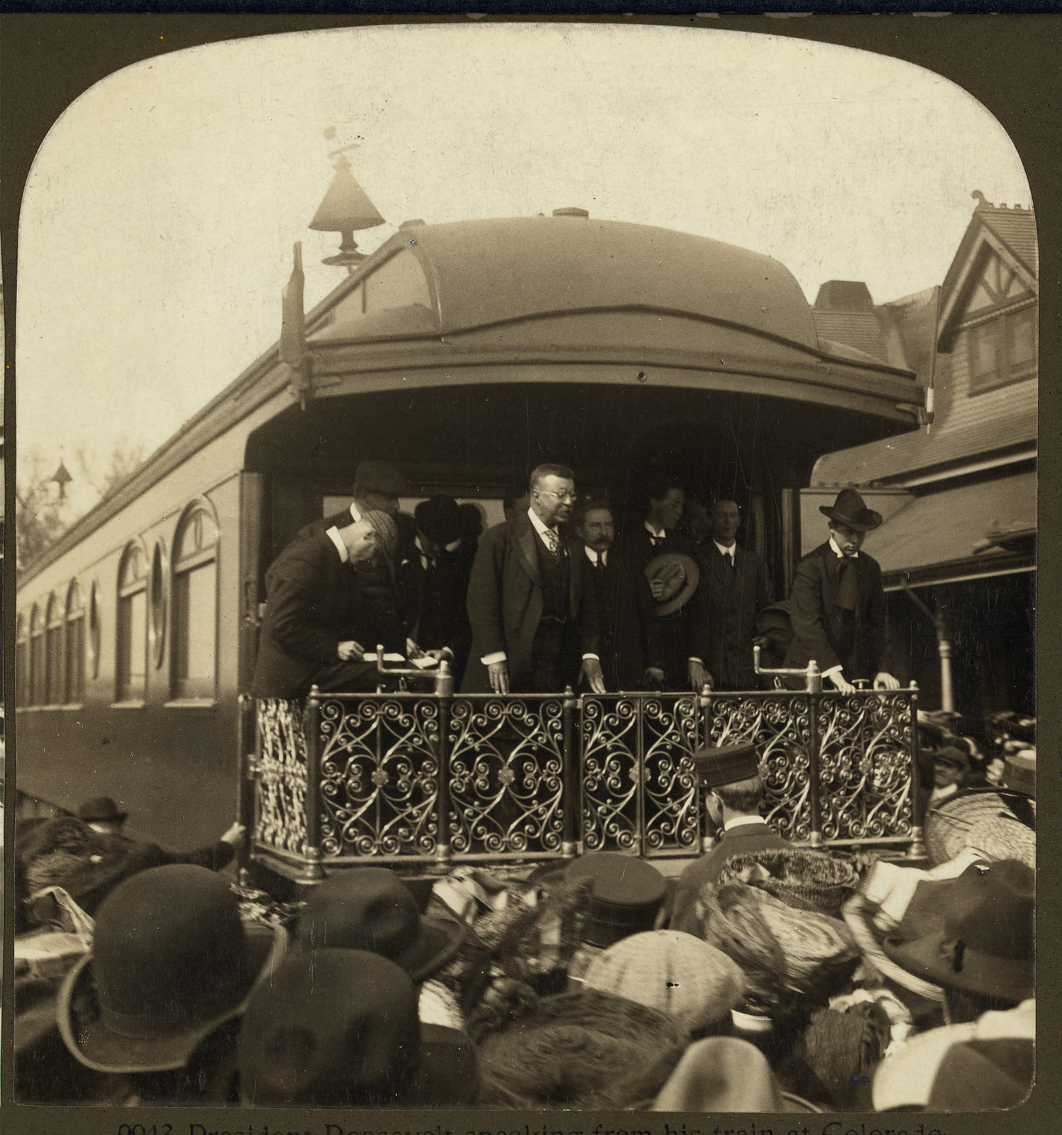 Man speaking from a train platform to a crowd — historic image