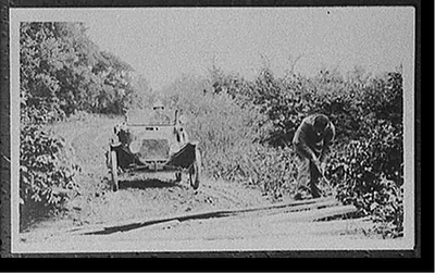 [Man clearing roadside brush]