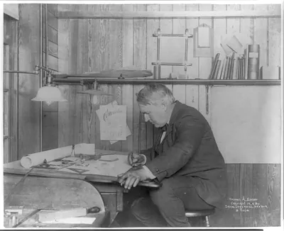 [Thomas Alva Edison, 1847-1931, left profile, seated at his desk, writing]
