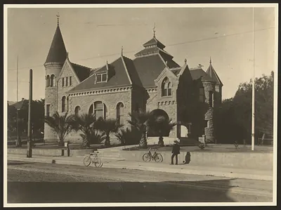 Stone building with turrets, palms and bicycles in street