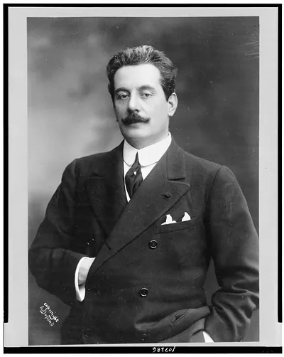 [Giacomo Puccini, half-length portrait, standing, facing slightly left, right hand inside coat]