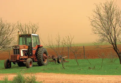 Red tractor under a dusty orange sky
