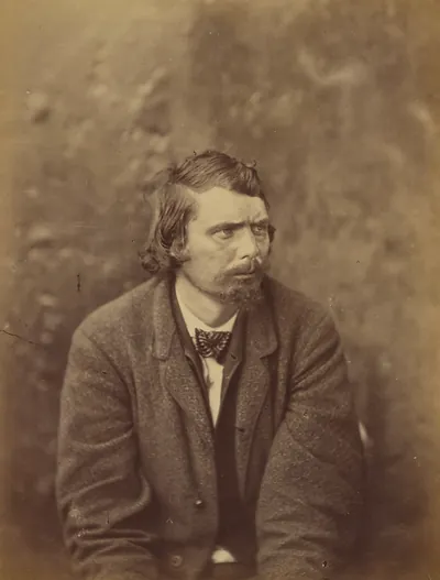 Seated man with bow tie, sepia studio portrait