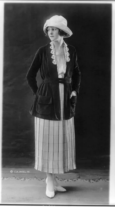 [Woman modeling skirt, blouse, coat, hat and shoes]