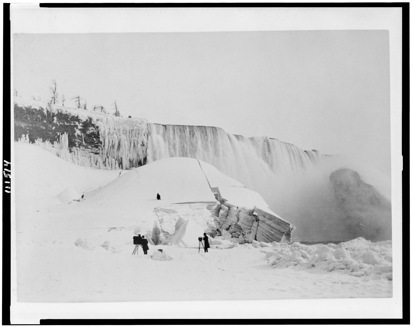 [Partly frozen falls, Niagara Falls, New York, with two photographers in front of frozen mass], [1900(?)] — historic photograph