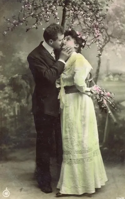 Couple kissing under blossoming tree, hand-colored photo postcard