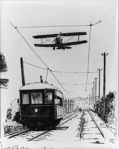 [Airplane racing above electric railway car]