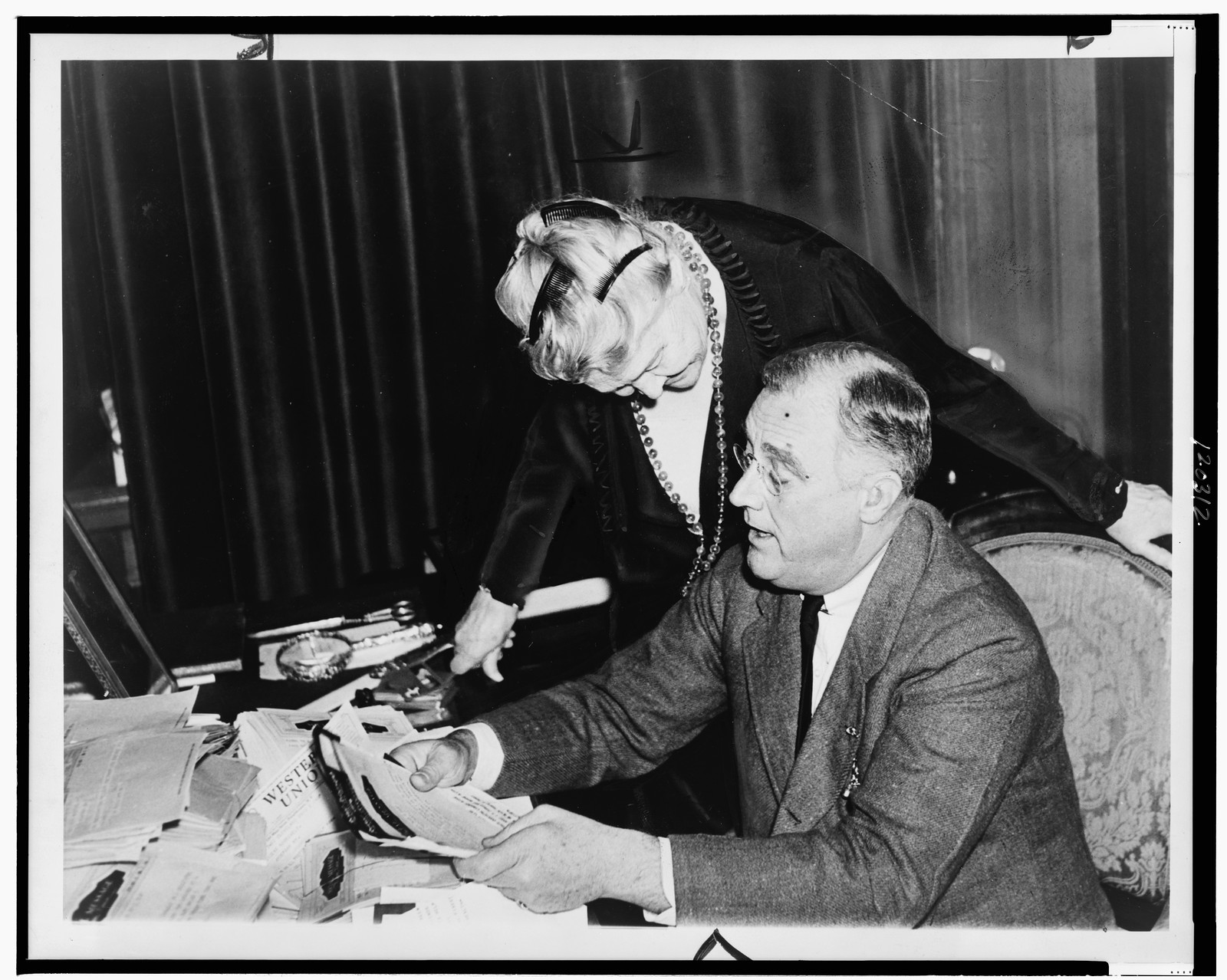 [President Franklin D. Roosevelt seated at desk with his mother, Mrs. James Roosevelt, reading congratulatory letters at his Hyde Park, New York, estate] — historic photograph