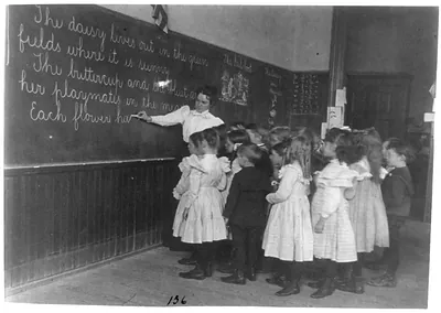 [Elementary school children standing and watching teacher write at blackboard, Washington, D.C.]