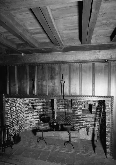 Historic kitchen fireplace with iron cooking pots and beamed ceiling