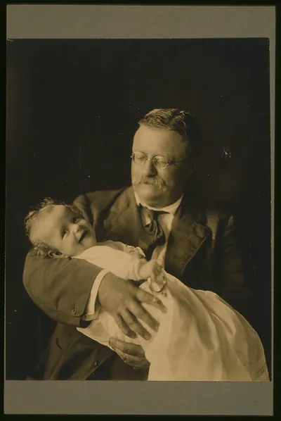 [Theodore Roosevelt, half-length portrait, seated, looking down, holding his grandchild, Kermit Roosevelt, Jr.]
