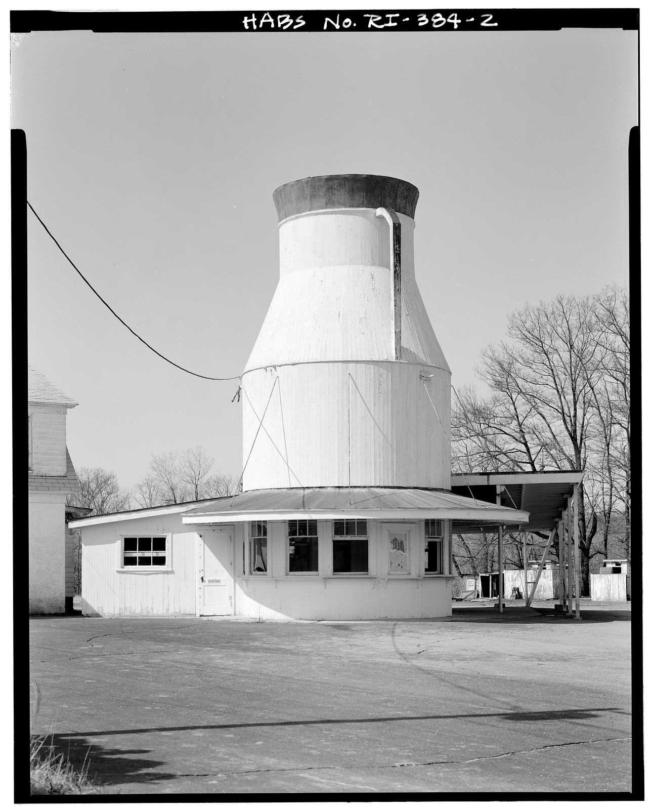 Milk can-shaped roadside building with attached white annex — historic image