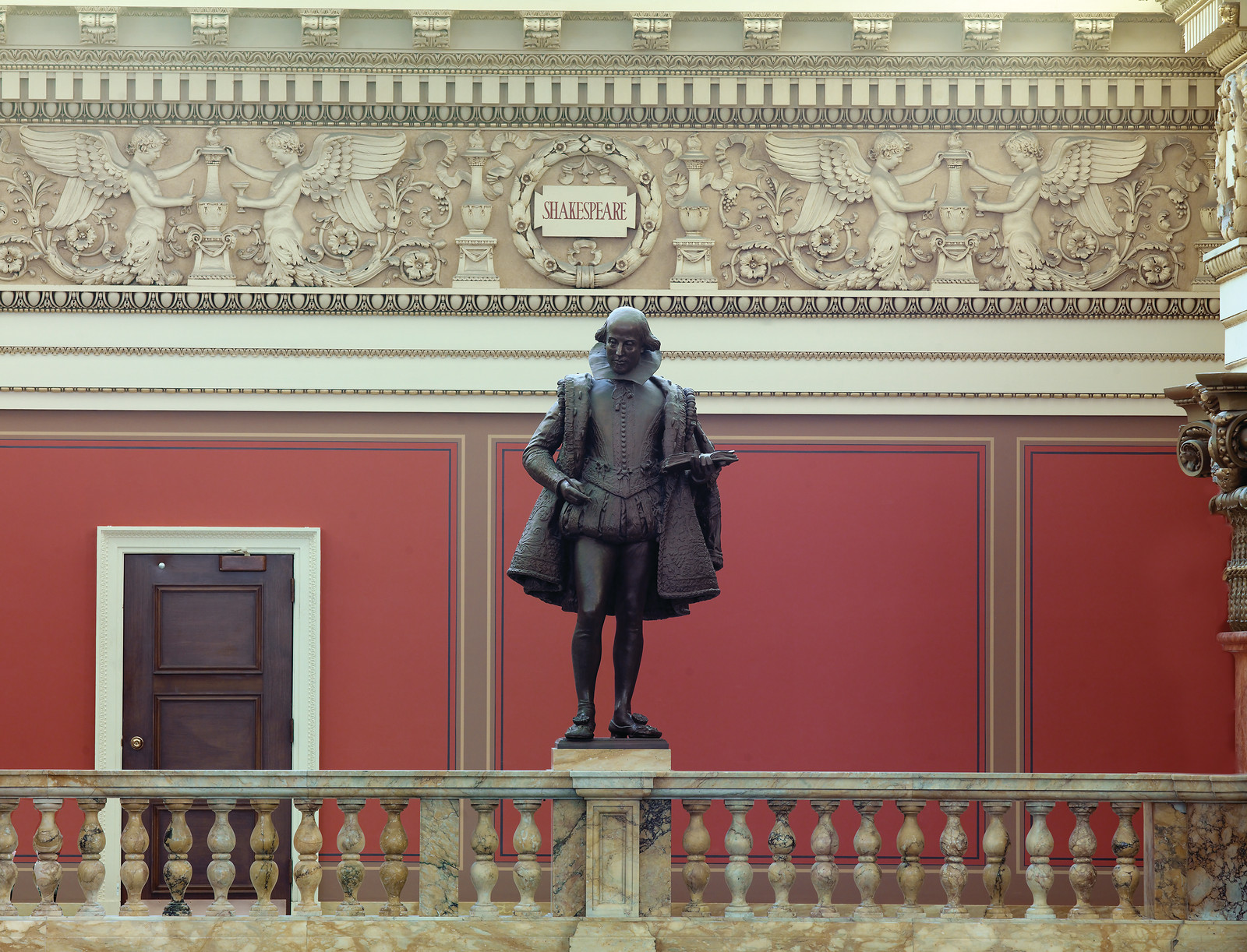 Bronze statue of Shakespeare beneath carved frieze inscribed SHAKESPEARE — historic image