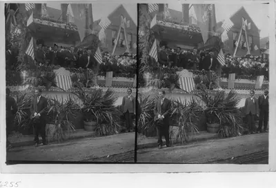 [Theodore Roosevelt and Booker T. Washington at decorated speaker's rostrum. Pres. Rooservelt holding a flower. Tuskegee Univ.?]