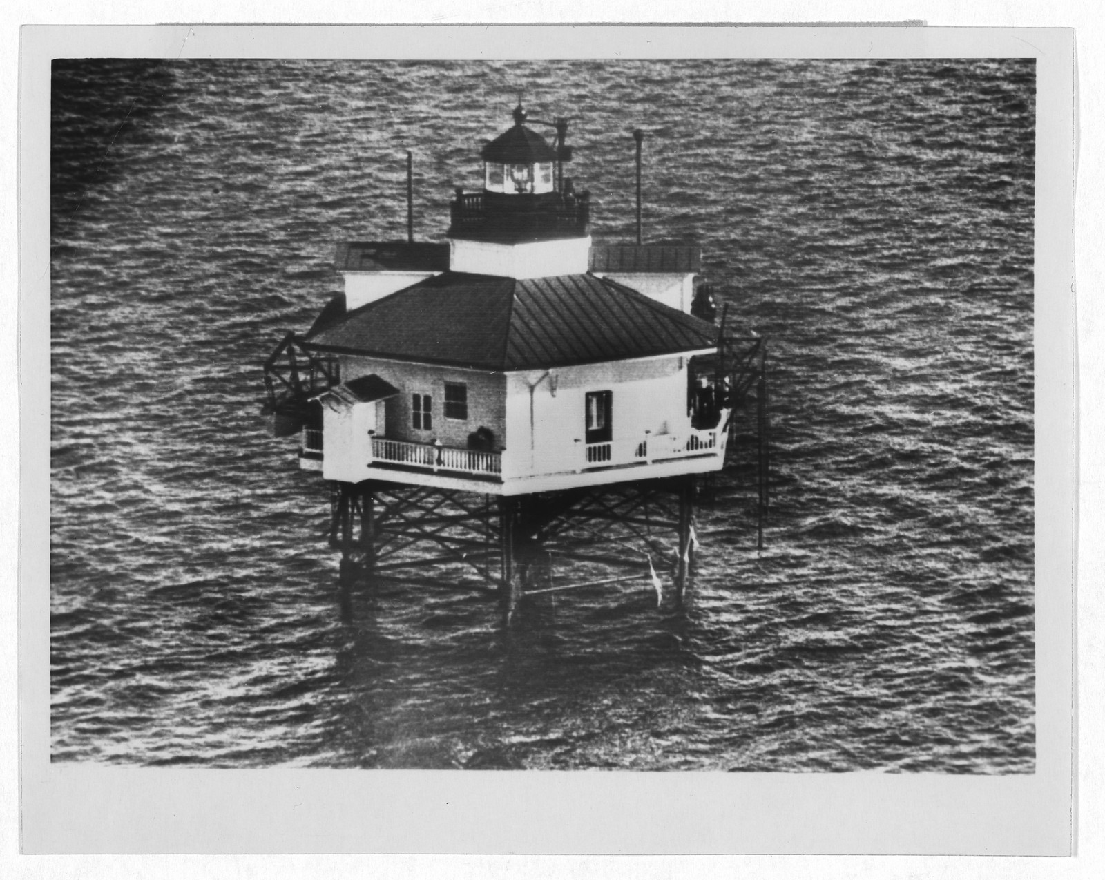 Offshore lighthouse on pilings, aerial black and white photograph — historic photograph