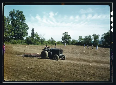 Tractor pulling a harrow across a farm field