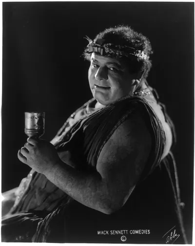 [Actor from Mack Sennett comedy film in Roman toga seated holding wine glass] / Abbe.