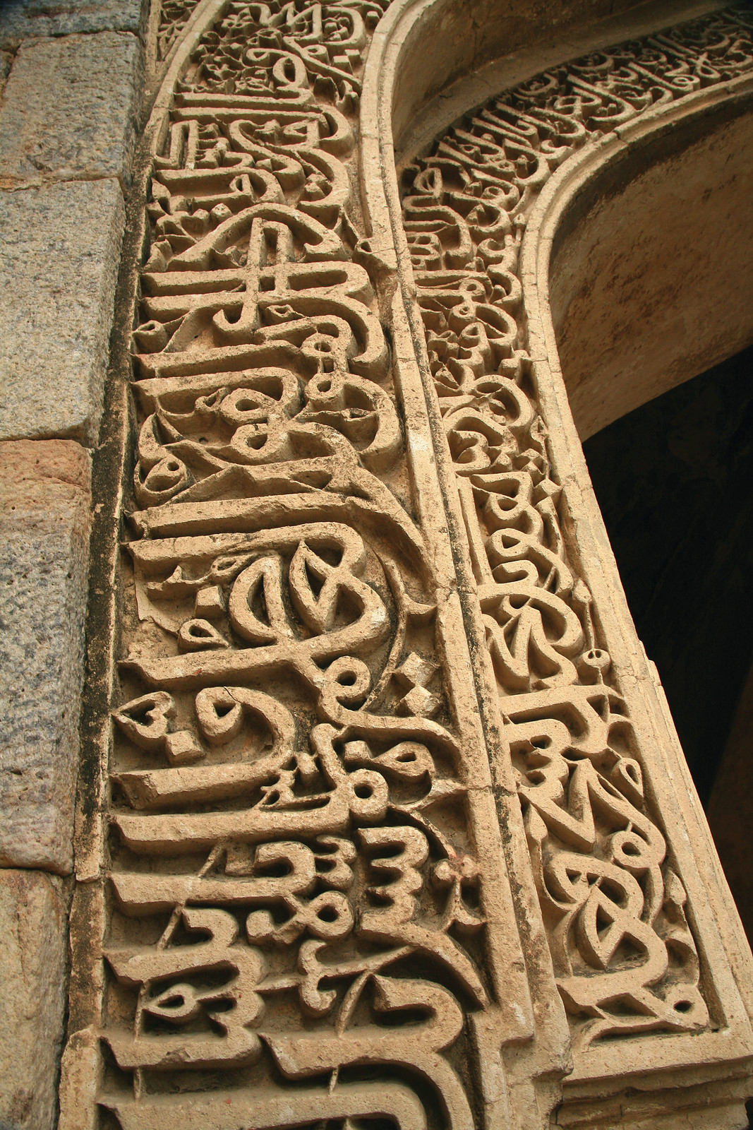 Carved Arabic inscription on a stone arch, Delhi mosque ruins — historic image