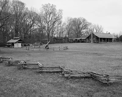 Log house and farm buildings in open field