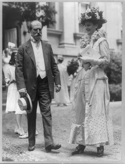 [Charles Evans Hughes, 1862-1948, full-length portrait, standing, facing right, and wife Antoinette (Carter) Hughes]
