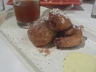 Fried dough balls dusted with sugar on a plate