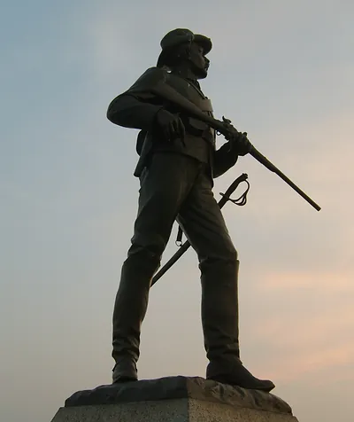 Bronze Civil War infantry soldier statue with rifle at sunset