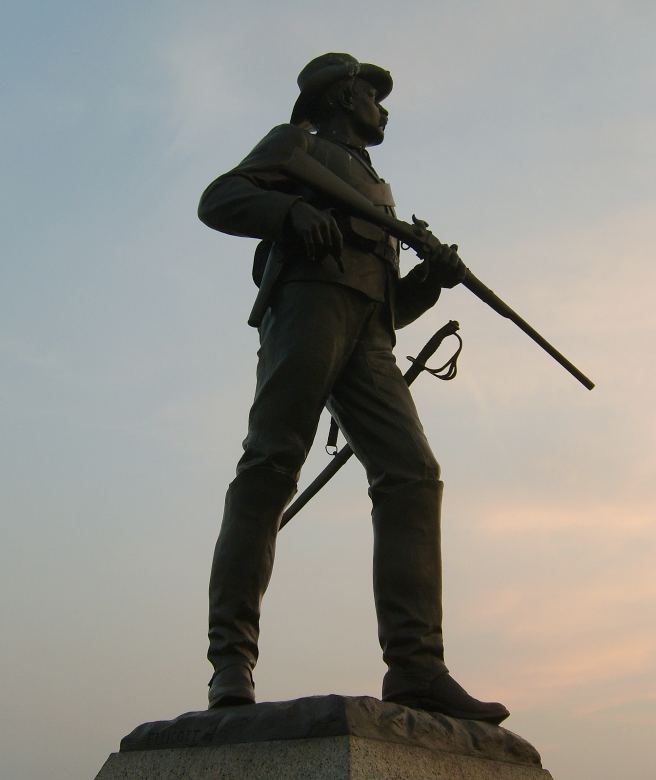 Bronze Civil War infantry soldier statue with rifle at sunset — historic image
