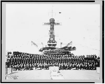 [Crew of the U.S.S. New Mexico posed on deck, on large guns, etc.]