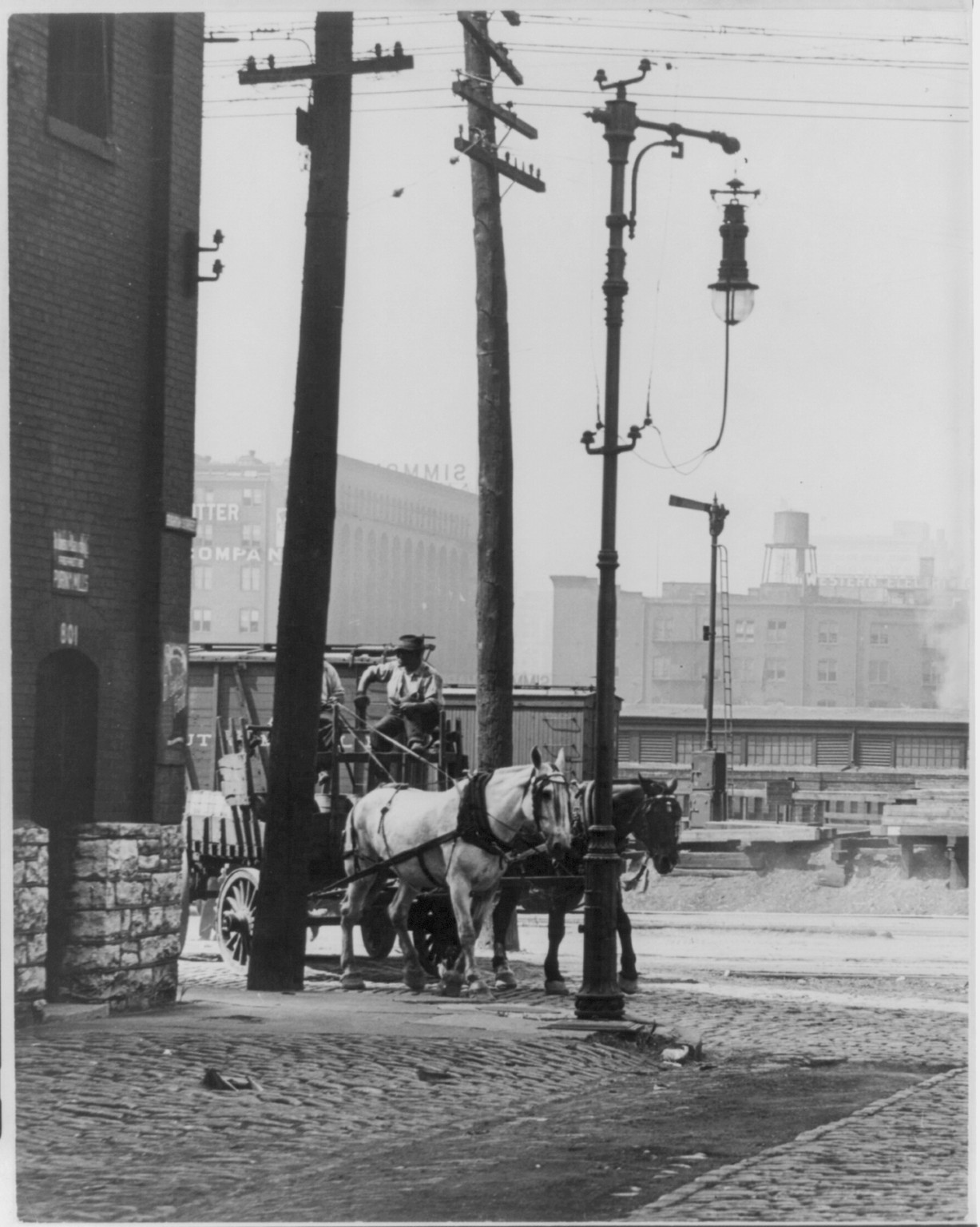 [Horse-drawn wagon, St. Louis, Mo. Electric street lamps in foregrd., western electric plant in backgrd.], [ca. 1900] — historic photograph