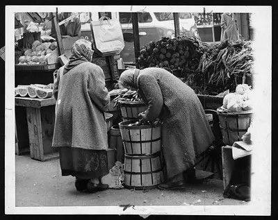 Two women examining produce at a market stall