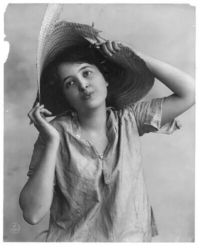 [Young woman modeling: Half lgth., wearing broken straw hat]