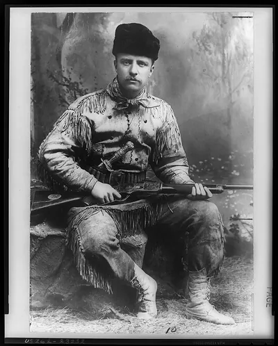[Theodore Roosevelt, full-length portrait, facing front, in deer skin hunting suit, rifle in hands]