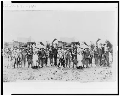 [Children posed in front of horse-drawn wagons and tents]