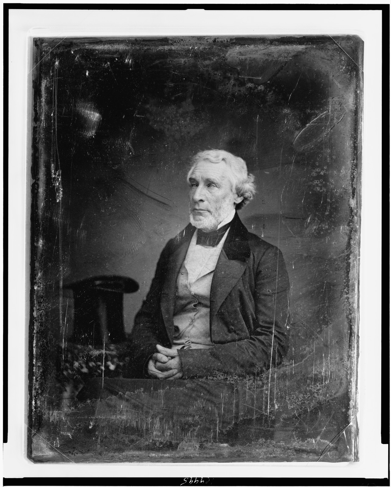 [James Gordon Bennett, three-quarter length portrait, three-quarters to the left, seated, hands folded in lap, seated beside a small table with tablecloth on which rests a tall hat], [between 1851 and 1852] — historic photograph