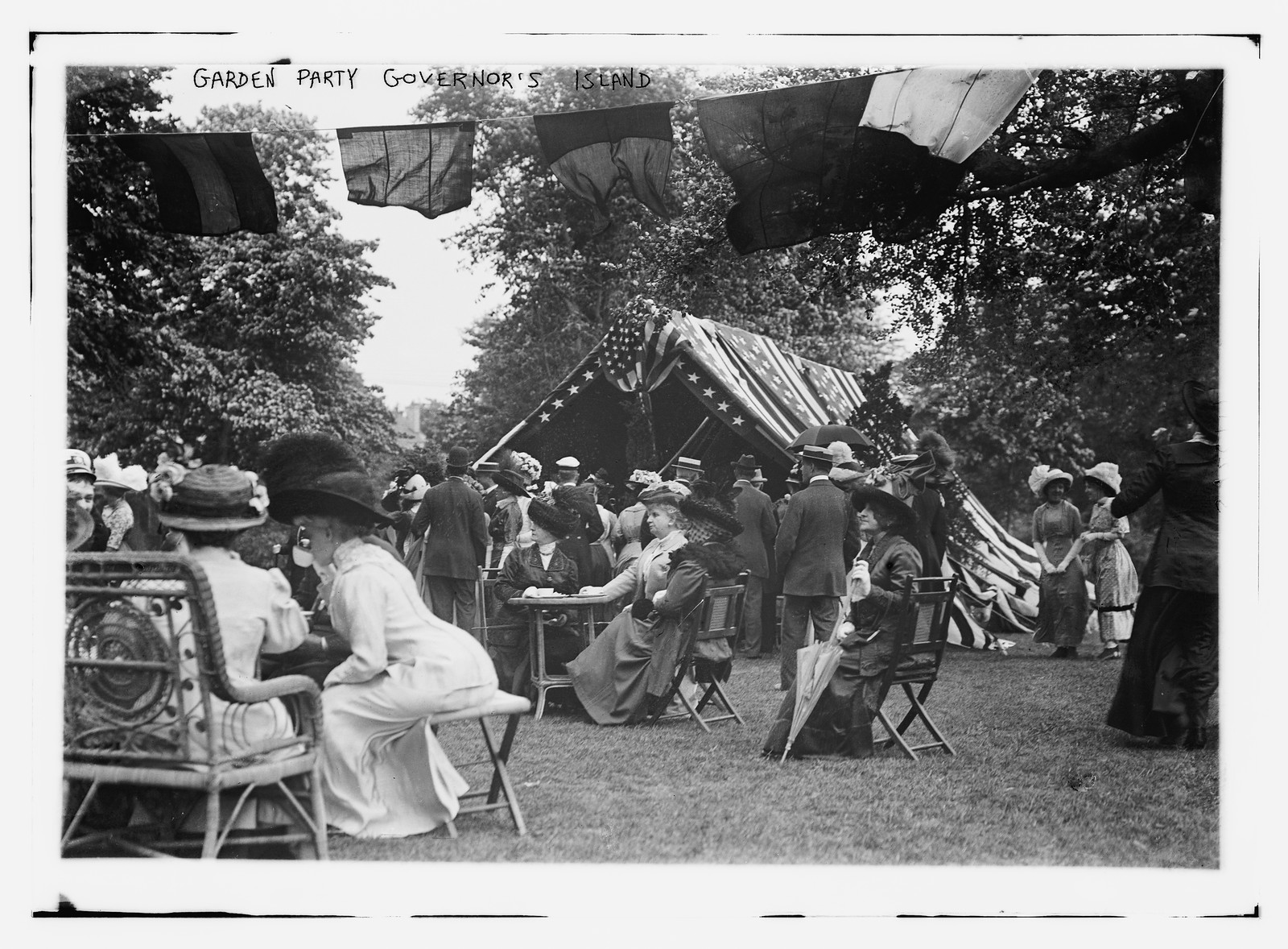 Garden party on Governor's Island with flags and guests — historic image