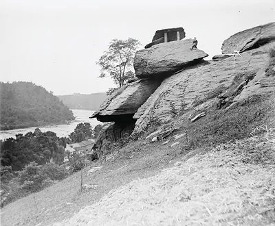 Rock outcrop above river with small shelter and man