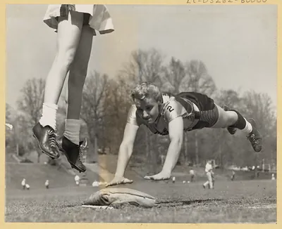 Women's baseball players sliding into base on a field