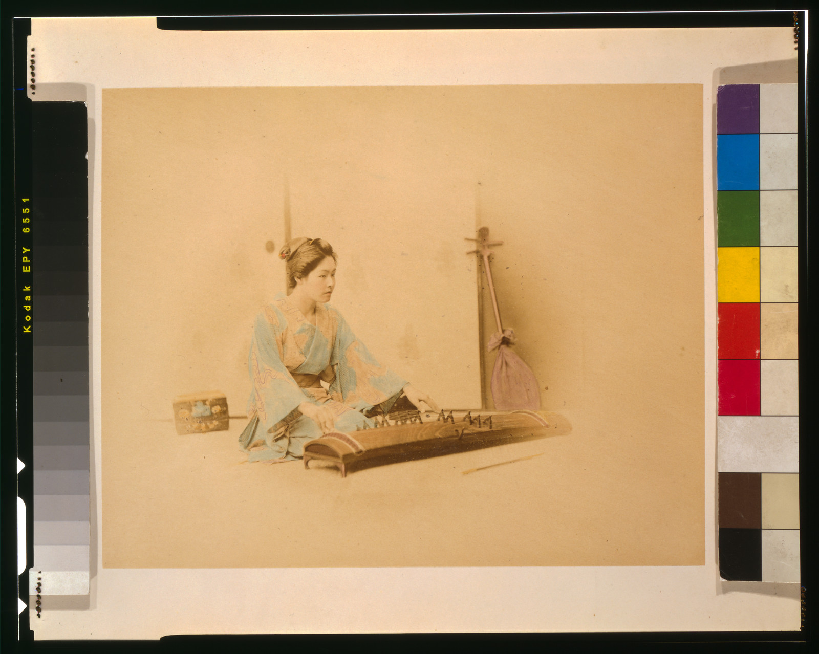 Hand-colored photograph of a woman playing koto — historic photograph