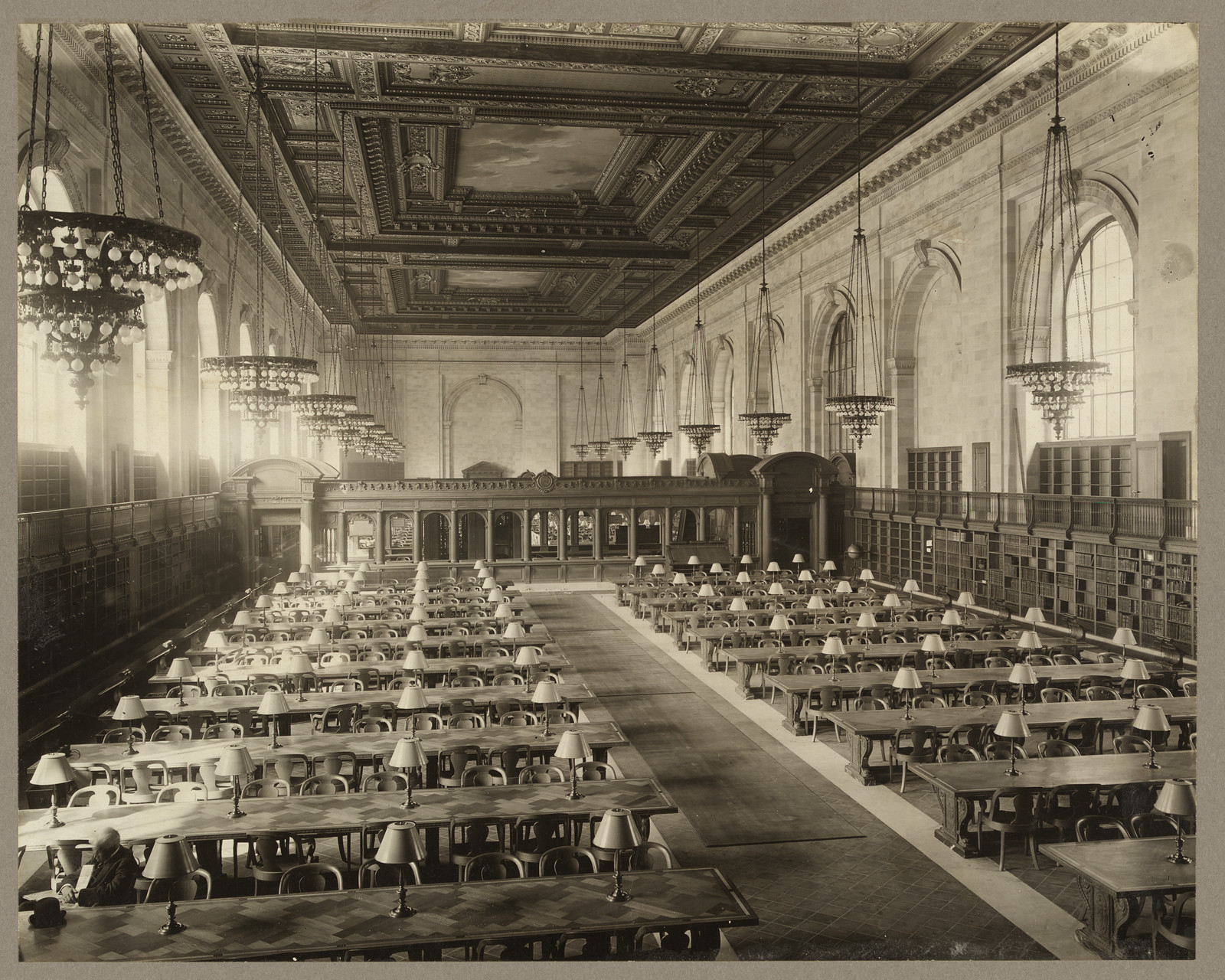 Large public library reading room with long tables and lamps — historic image
