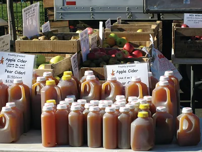 Jugs of apple cider and pear cider at a market stall