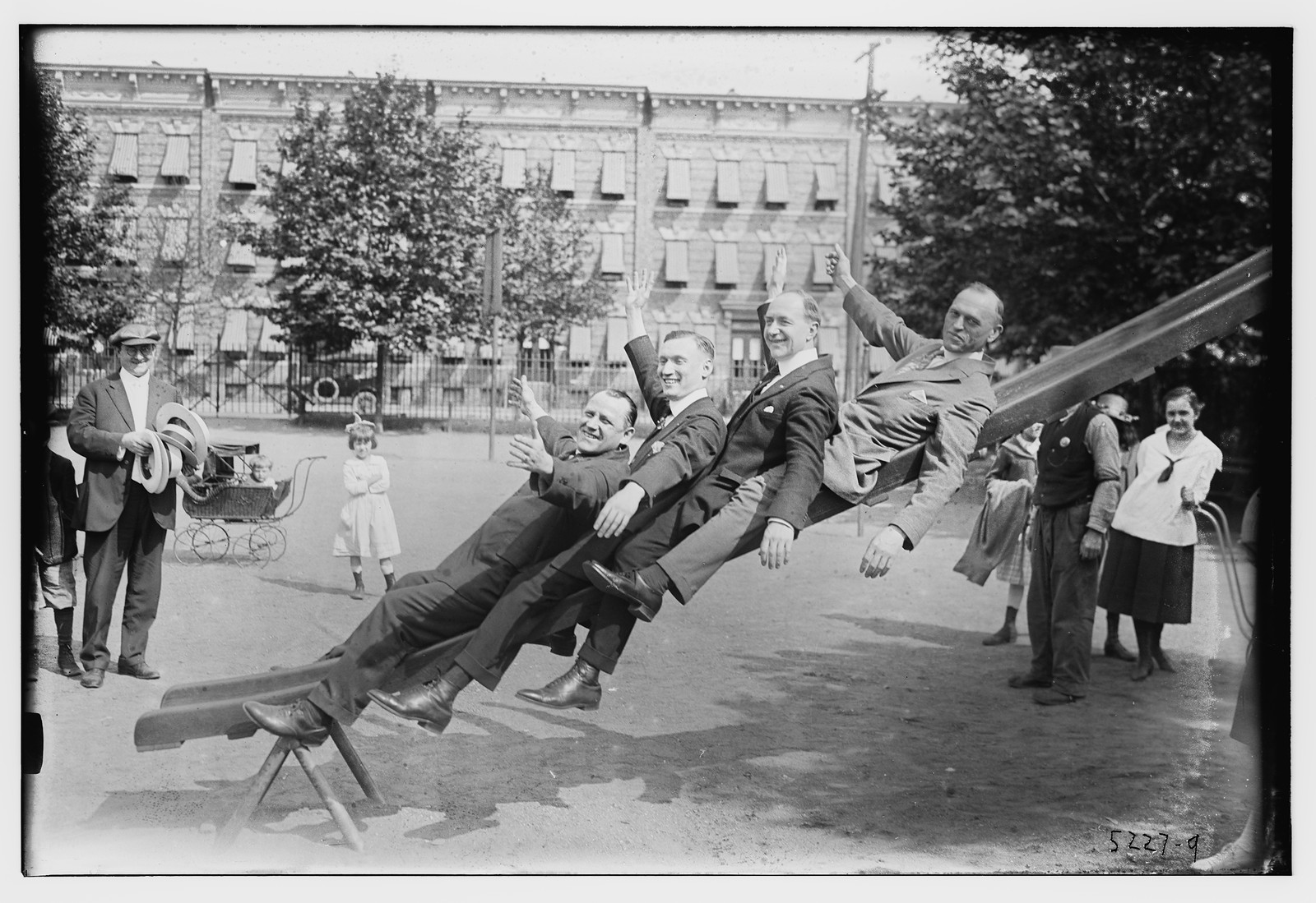 4 men on slide in park, n/a — historic photograph