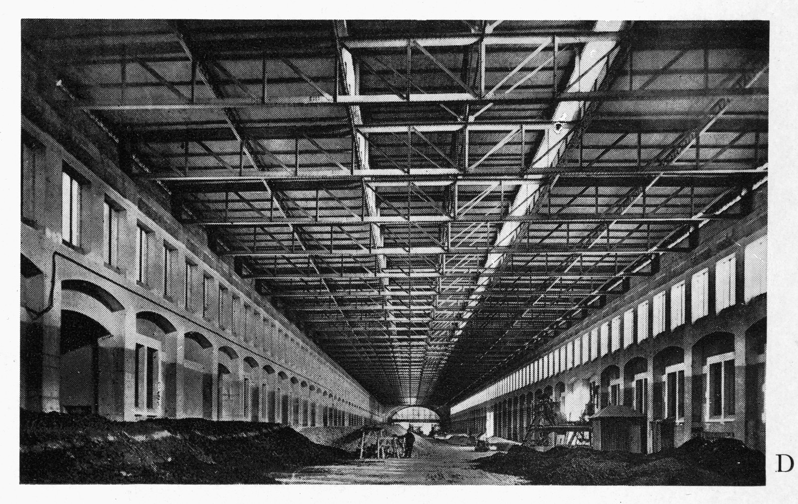 Interior of a long covered hall with steel trusses and arches — historic image